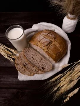 Rustic loaf of bread with slices and a glass of milk Stock Photos