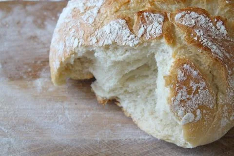 Rustic loaf of homemade bread close up on wooden board. Broken bread overhead vi Stock Photos