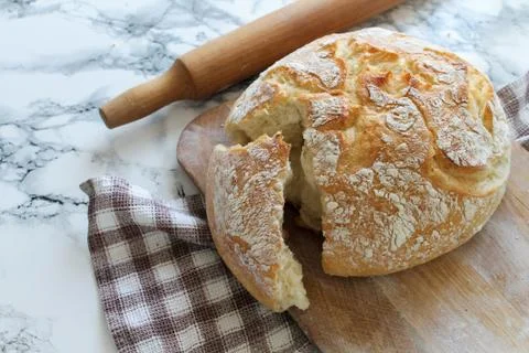 Rustic loaf of homemade bread close-up on wooden board on linen napkin with rock Stock Photos