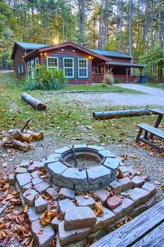 Rustic Log Cabin and Fire Pit in Autumn Forest Aerial Foto stock