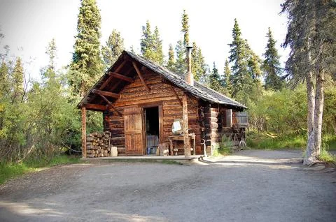 Rustic log cabin in a dense forest, exuding a cozy wilderness charm. Stock Photos