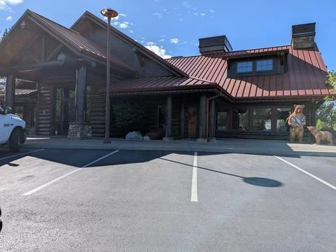 Rustic log cabin with a dramatic bear-and-fish statue Photos