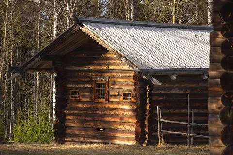 Rustic log cabin surrounded by trees in a field, with a cozy cottage feel Stock Photos
