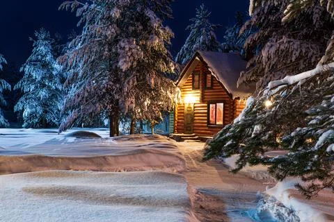 Rustic log house, snow-covered pine trees, big snowdrifts, fabulous winter night Stock Photos