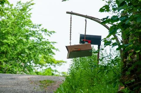Rustic mailboxes hanging from a wooden post on a rural road Stock-Fotos
