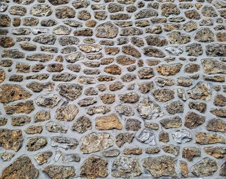 Rustic masonry wall made of natural stones set in grey mortar in a Mediterr.. Fotos Stock