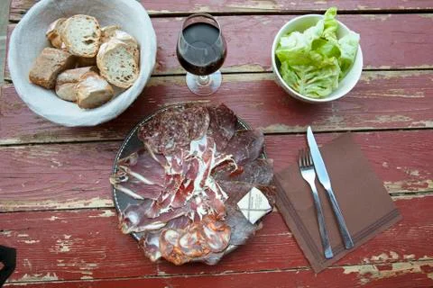 A rustic meat platter with bread, red wine and lettuce Stock Photos