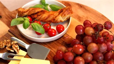 Rustic Mediterranean display with golden bread twist, deep red grapes, fresh Stock Photos