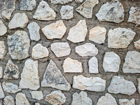 Rustic Mediterranean stone wall with uneven natural rocks set in grey morta.. Stock Photos