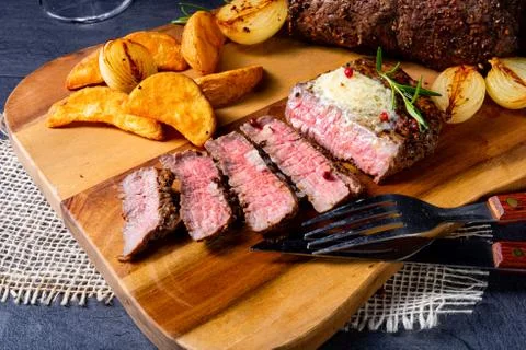Rustic medium butter beef steak with herbs and potato wedges Stock Photos