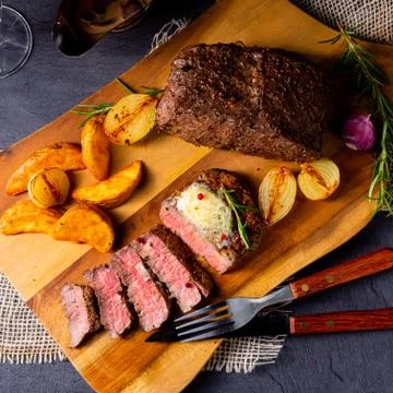 Rustic medium butter beef steak with herbs and potato wedges Stock Photos