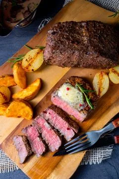 Rustic medium butter beef steak with herbs and potato wedges Stock Photos