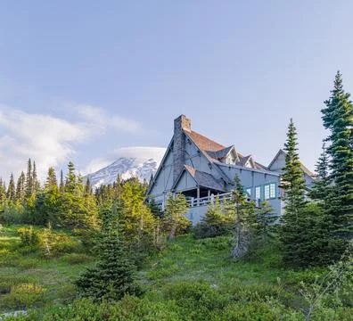 Rustic mountain lodge with snow-capped peak and evergreen forest Photos