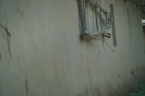 Rustic mud wall of a rural house in Bangladesh with a simple wooden window frame Stock Photos