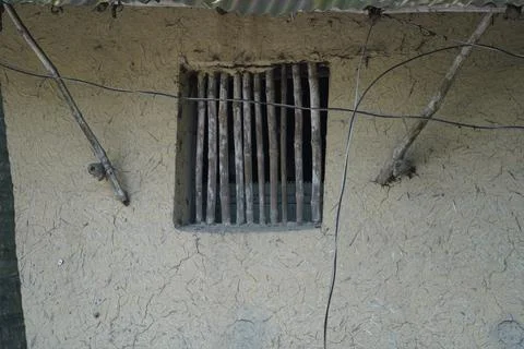Rustic mud wall with a wooden slatted window in a traditional rural village home Stock Photos