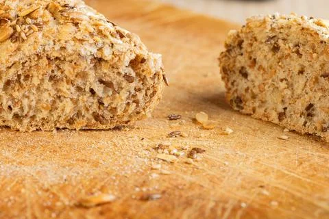 Rustic multigrain bread loaf sliced on wooden cutting board. Stock Photos