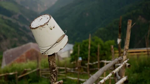 Rustic old metal bucket atop a wooden post in a pastoral setting with Stock Footage 265498583