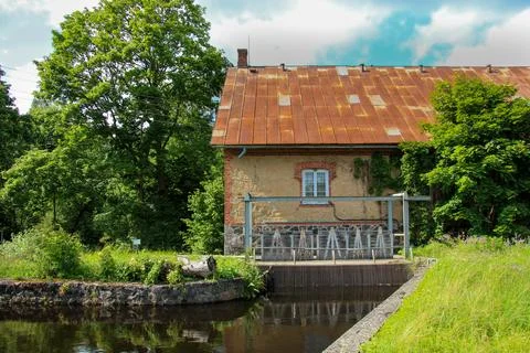 Rustic Old Mill Building with Rusty Roof and Waterway Foto stock