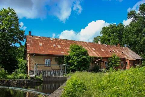 Rustic Old Mill Building with Rusty Roof and Waterway Foto stock