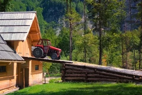 Rustic old red tractor on ramp of wooden barn Stock Photos