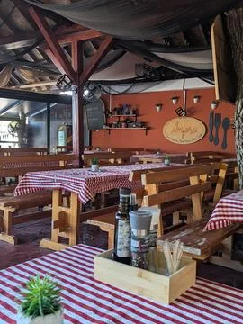 Rustic open air restaurant interior with wooden benches checkered tablecloths Stock Photos