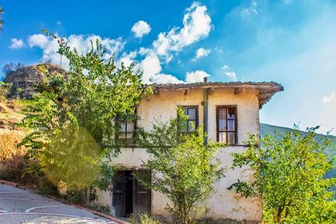 A rustic Ottoman house surrounded by greenery under a bright blue sky. Stock Photos