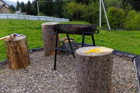 A Rustic Outdoor Cooking Setup Featuring a Grill, Stumps, and Tools for a Stock Photos