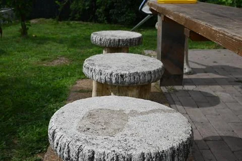Rustic outdoor stone stools beside a wooden table Stock Photos