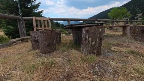 Rustic outdoor table and chairs at mountain refuge with fir forest view Stock Footage 327560447
