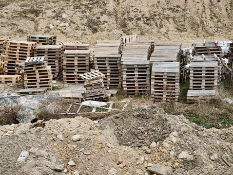 Rustic pallets awaiting reuse. Organized rows of aged pallets on dusty quar.. 库存照片