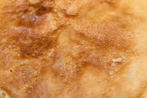 Rustic pancake displaying uneven browning and porous texture. Macro photograp Stock Photos