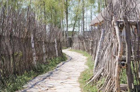 A rustic path paved with stone and a wooden fence made of natural nature mate Stock Photos
