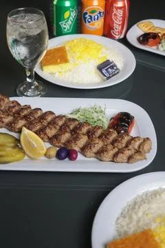 Rustic Persian dining scene featuring koobideh kebabs with saffron rice Stock Photos
