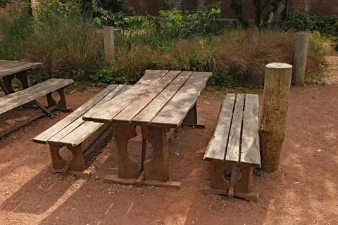 A rustic picnic table and bench in a playground 스톡 사진