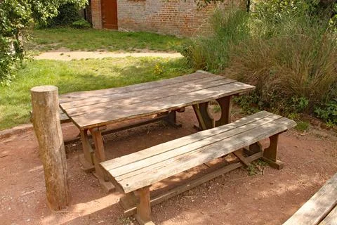 A rustic picnic table and bench in a playground 스톡 사진