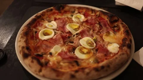 Rustic pizza with ham boiled eggs and golden crust in a warm cozy food scene Stock Footage 328286613