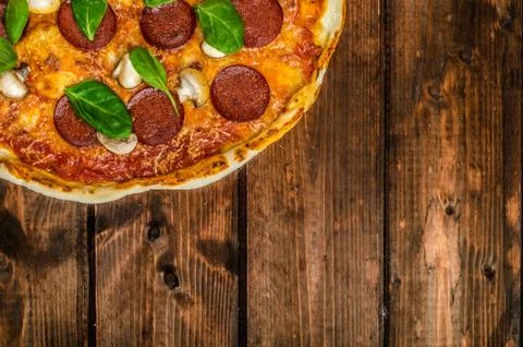 Rustic pizza with salami, mozzarella and spinach Stock Photos