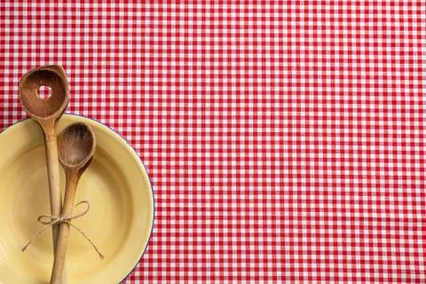 Rustic place setting. Empty plate, wooden kitchen utensils and red tablecloth Stock Photos