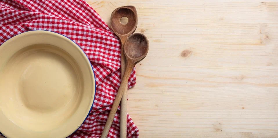 Rustic place setting. Empty plate, kitchen utensils and red tablecloth on woo Stock Photos