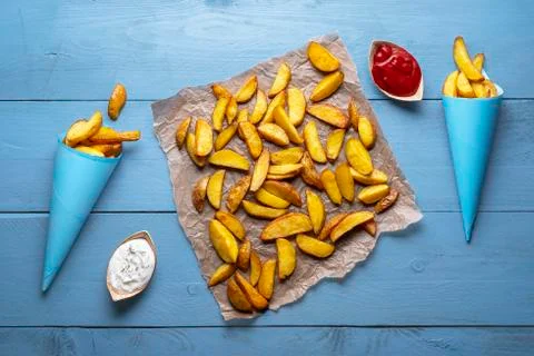 Rustic potatoes in paper cones on table. Roast potatoes. Baked wedges Stock Photos