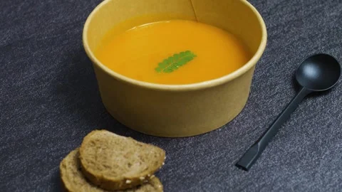 Rustic pumpkin soup nestled in ceramic bowl, accompanied by whole wheat bread Video stock 314890064
