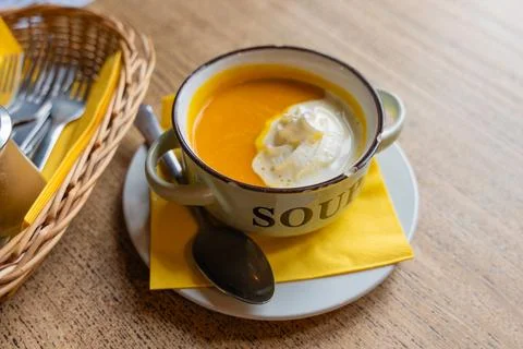 Rustic pumpkin soup served in enamel mug with chipped edge on wooden table Stock Photos