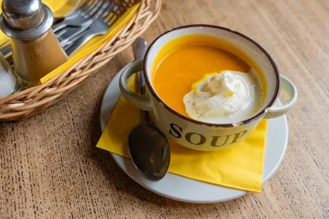 Rustic pumpkin soup served in enamel mug with chipped edge on wooden table Stock Photos
