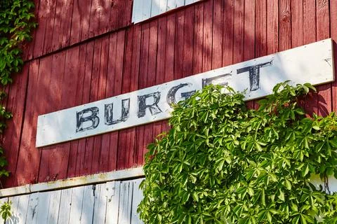 Rustic Red Barn with Vintage 'Burget' Sign and Climbing Vine Close-Up Stock-Fotos
