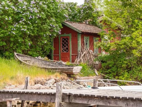 Rustic Red Cabin by the Water with Lush Greenery Stock Photos