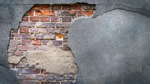 Rustic red corroded brick hole in a grey plaster wall Stock Photos
