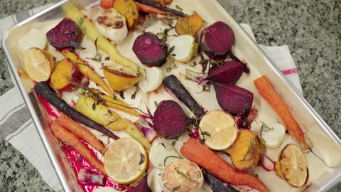 Rustic roasted root vegetables with garlic, lemon, and thyme on a baking tray Stock Footage 296735356