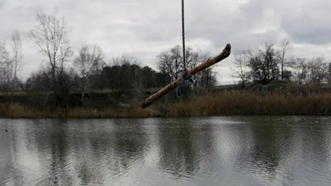 Rustic Rope Swing Over a Calm River on a Gloomy Day Stock Footage 324823735