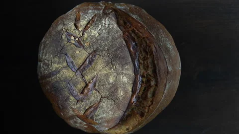 Rustic round loaf of freshly baked sourdough bread, rotating, close up Stock Footage 296529134