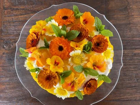 Rustic round sweet cake decorated with orange and yellow flowers and green mint  Stock Photos